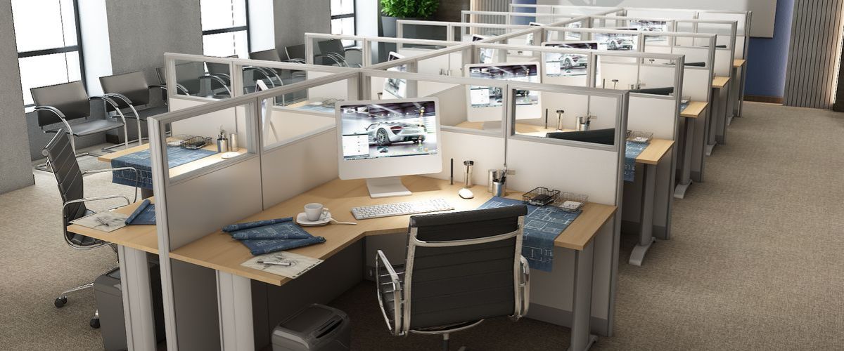 A modern office cubicle with an L-shaped desk. The desk wraps around in an L-shape, providing ample workspace on both sides.