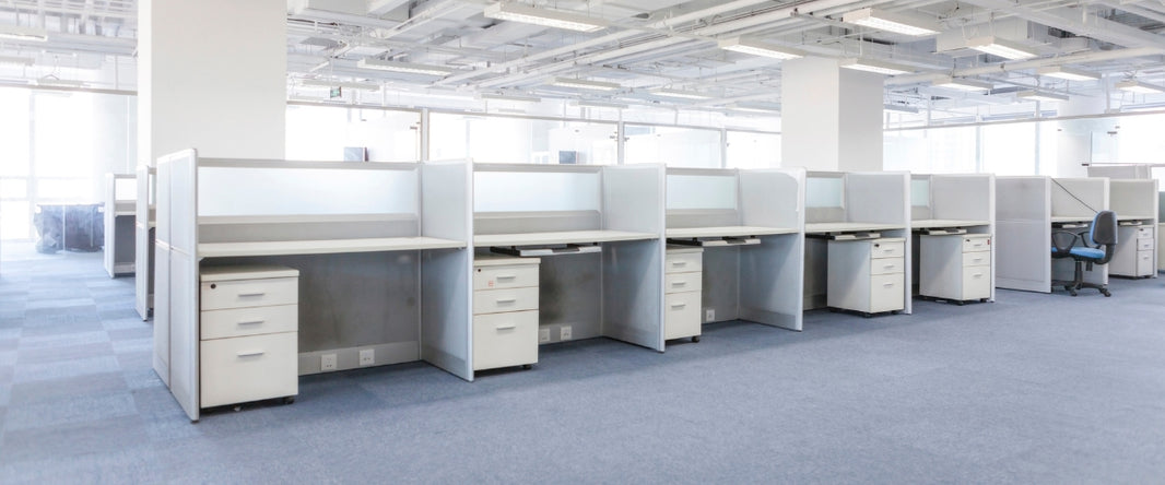 A long row of eight gray office cubicles with white desks and chairs.