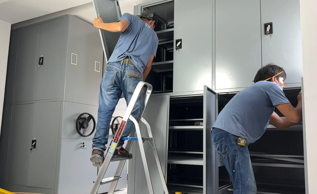 Technicians installing a file compactor system in the Philippines, featuring large, gray metal cabinets with adjustable shelving, rotating handles, and lockable compartments for secure and organized file storage.