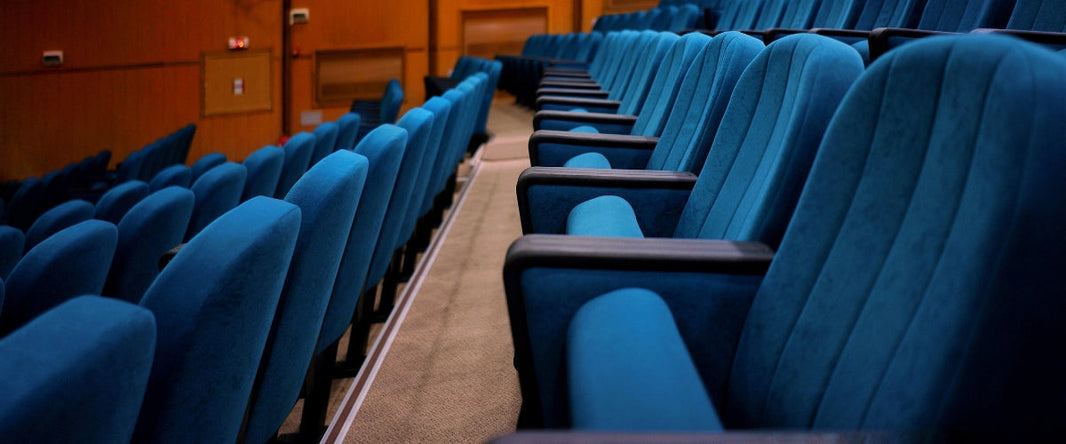 Close-up view of tiered blue auditorium chairs with cushioned seats and armrests in a modern venue