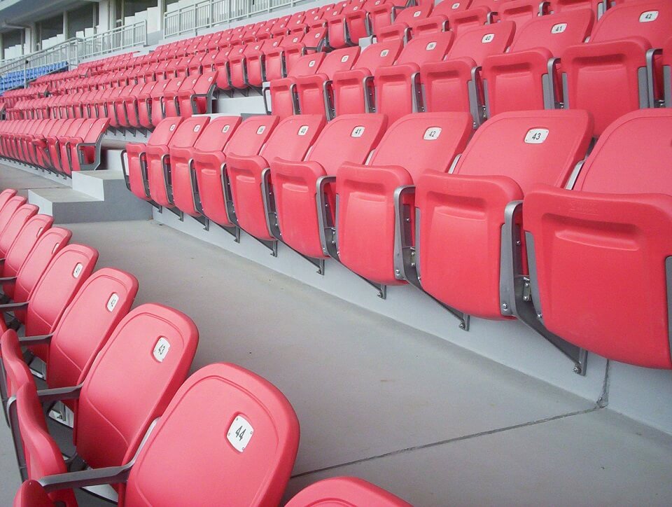 bleacher seats in red plastic and gray aluminum alloy legs in a sports complex in the philippines