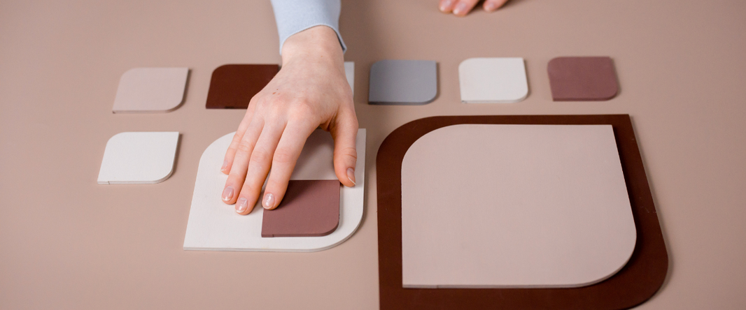 A person holding a framed Pantone color swatch in Mocha Mousse, with a flower arrangement in the background.