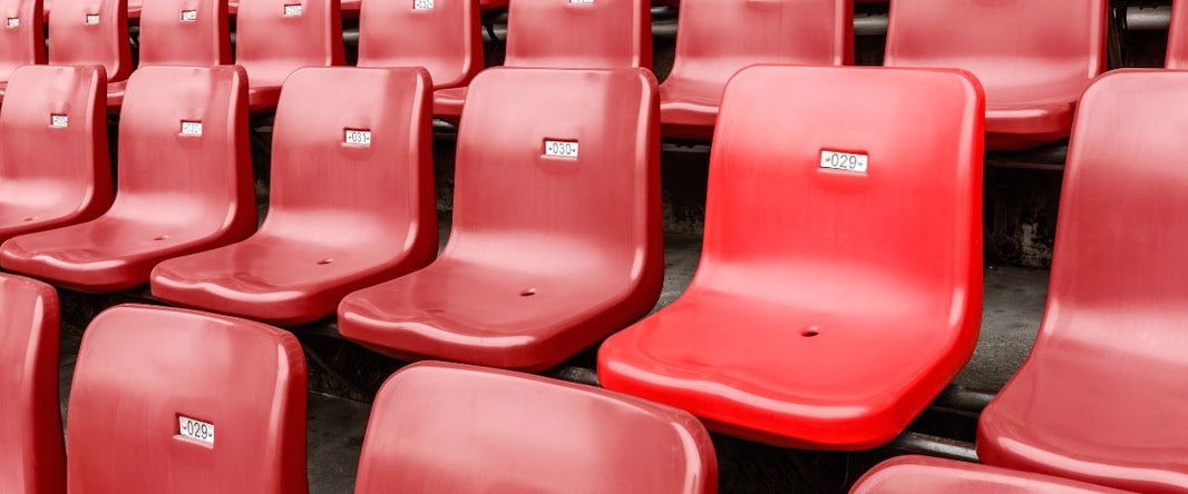 A sleek red bleacher chair made of durable plastic with a smooth, contoured seat and backrest, designed for comfort and support