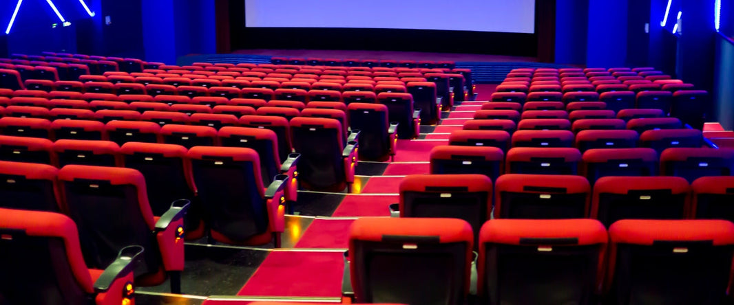 comfortable theater seating with cushioned chairs, armrests, and built-in cup holders, offering a clear view of the stage in a well-lit theater