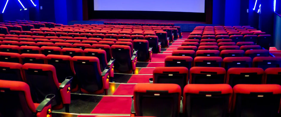 comfortable theater seating with cushioned chairs, armrests, and built-in cup holders, offering a clear view of the stage in a well-lit theater